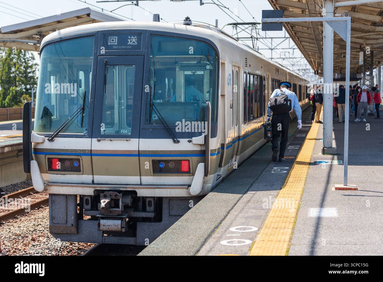 Otsu, Shiga, Giappone. Treno locale JR West che ferma alla piattaforma della stazione di Omi-Maiko, con un conduttore che cammina lungo la piattaforma. Foto Stock