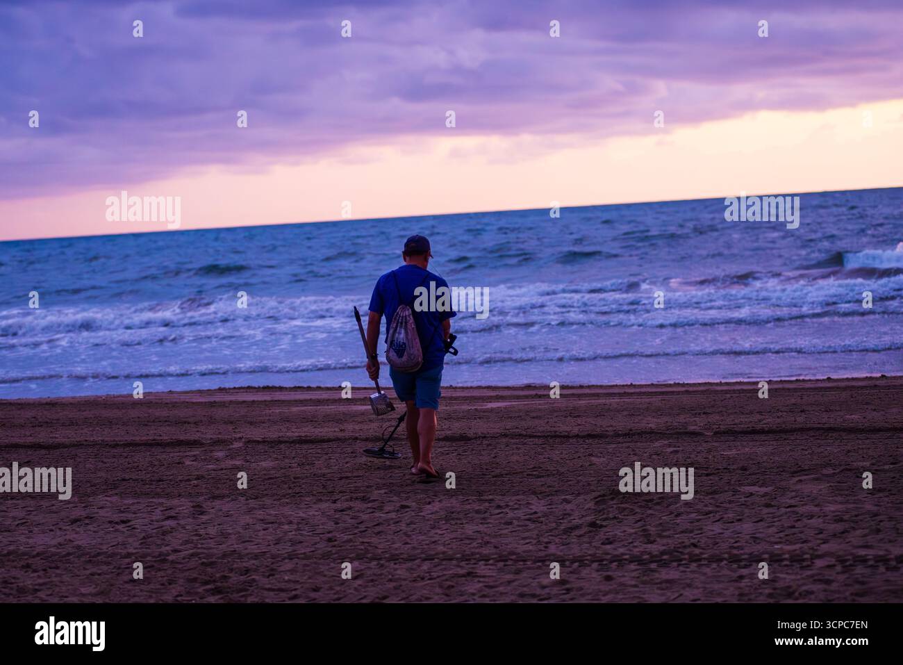 Uomo che pettina la spiaggia con il metal detector Foto Stock