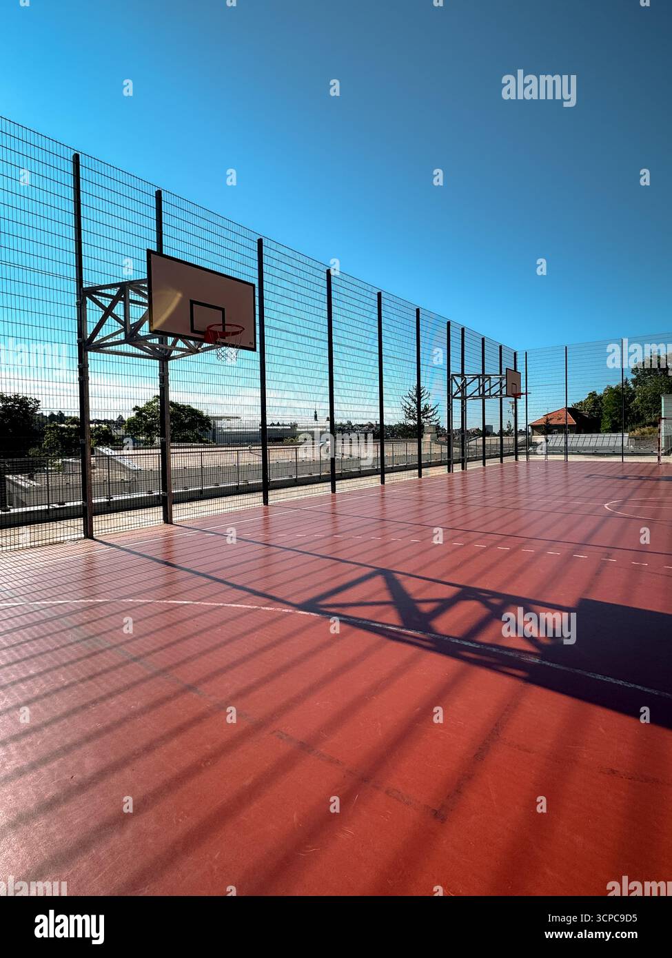 Un campo da pallacanestro all'aperto, arroccato sopra la città alta di Zagabria, circondato da scherma e inondato dalla luce del mattino, si affaccia sulla città sottostante. Foto Stock