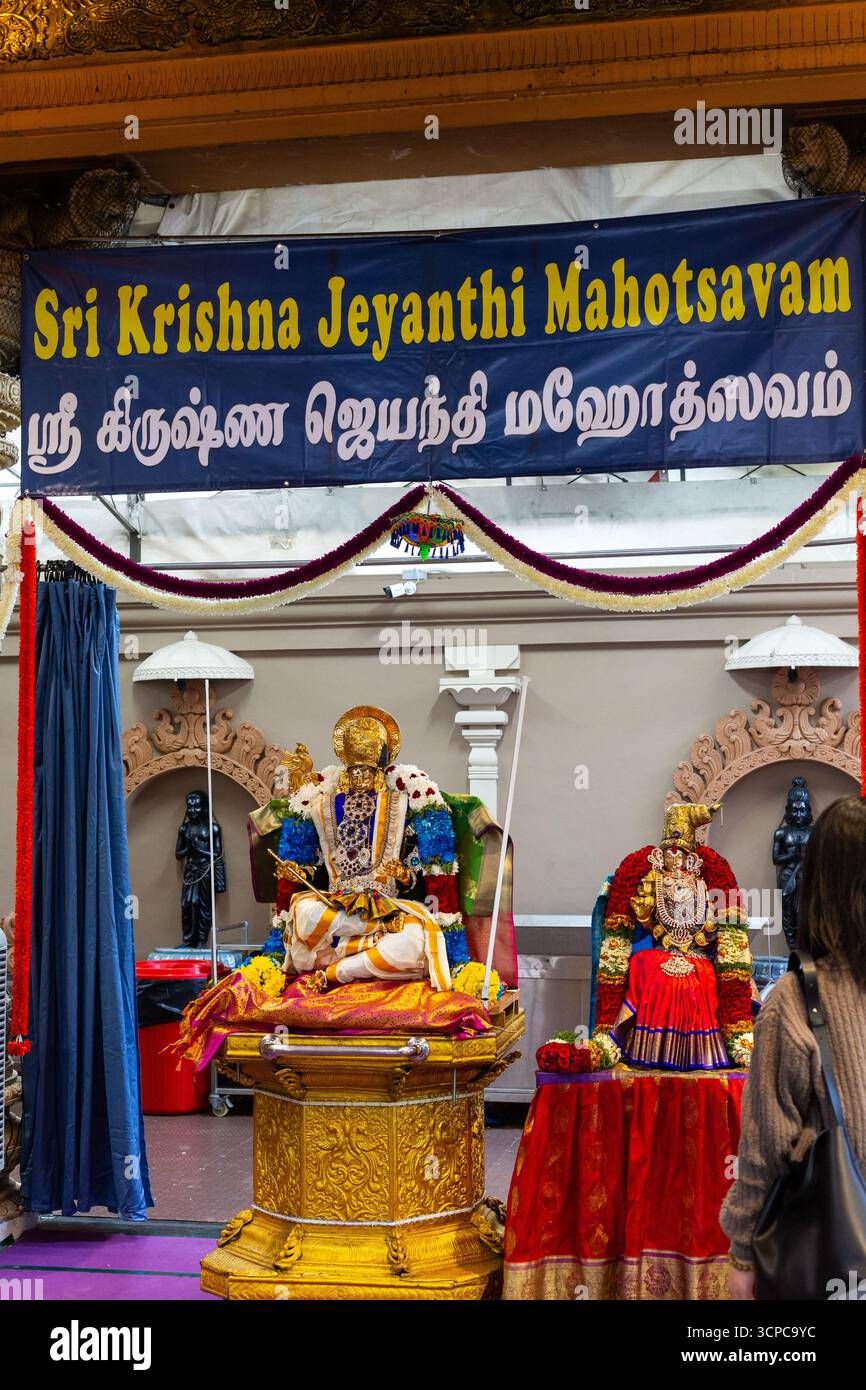 Vista verticale. Sri Krishna Jeyanthi Mahotsavam, celebrazione dell'evento, vista posteriore della donna asiatica che presta rispetto al dio. Tempio indù a Singapore. Foto Stock