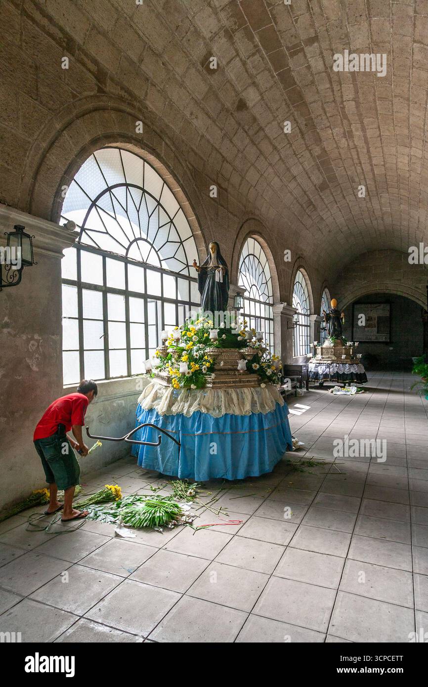 Un uomo decora una carrozza processionale con un'immagine di un santo agostiniano al monastero di San Agustin, Intramuros, Manila Foto Stock