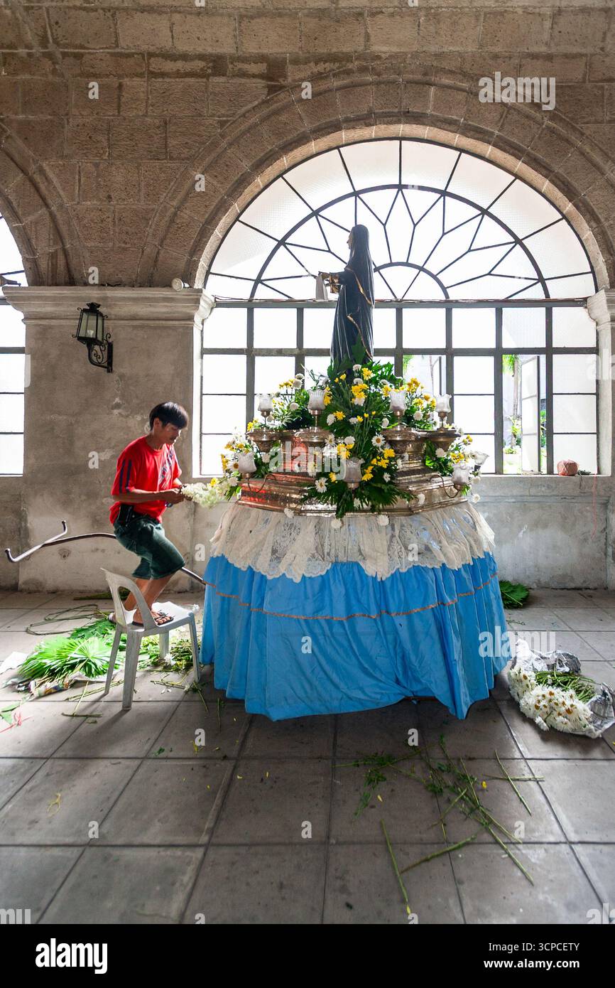 Un uomo decora una carrozza processionale con un'immagine di un santo agostiniano al monastero di San Agustin, Intramuros, Manila Foto Stock
