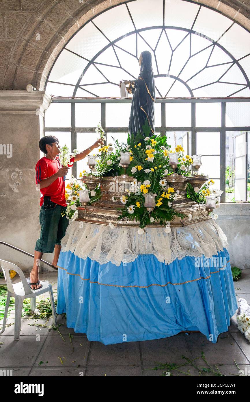 Un uomo decora una carrozza processionale con un'immagine di un santo agostiniano al monastero di San Agustin, Intramuros, Manila Foto Stock