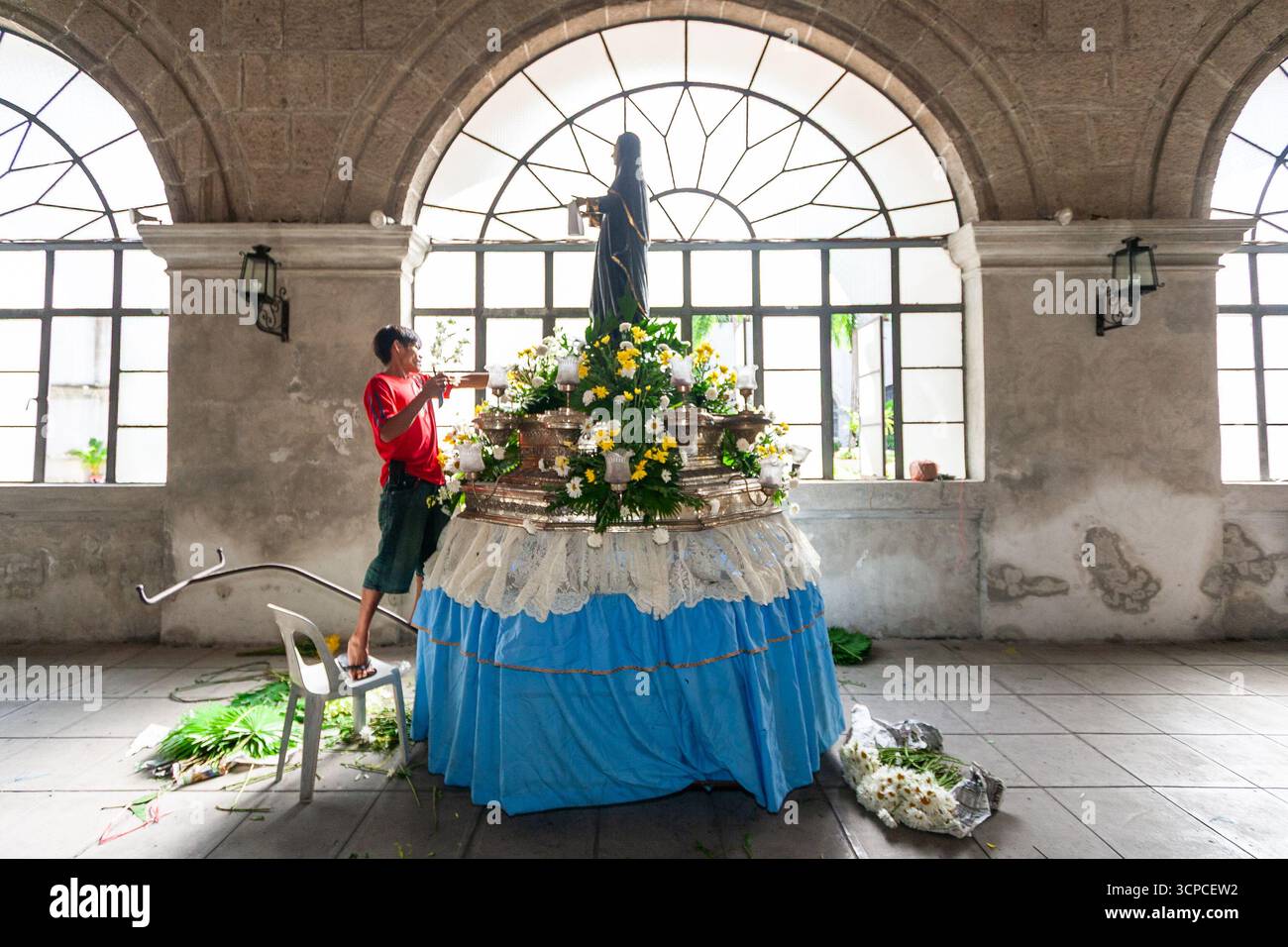 Un uomo decora una carrozza processionale con un'immagine di un santo agostiniano al monastero di San Agustin, Intramuros, Manila Foto Stock