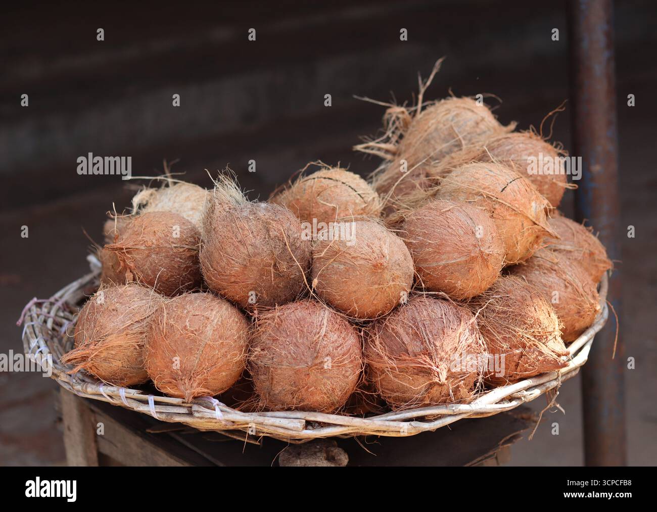 Cocchi di cocco sbucciati in esposizione per la vendita in un cesto intrecciato tradizionale. Foto Stock