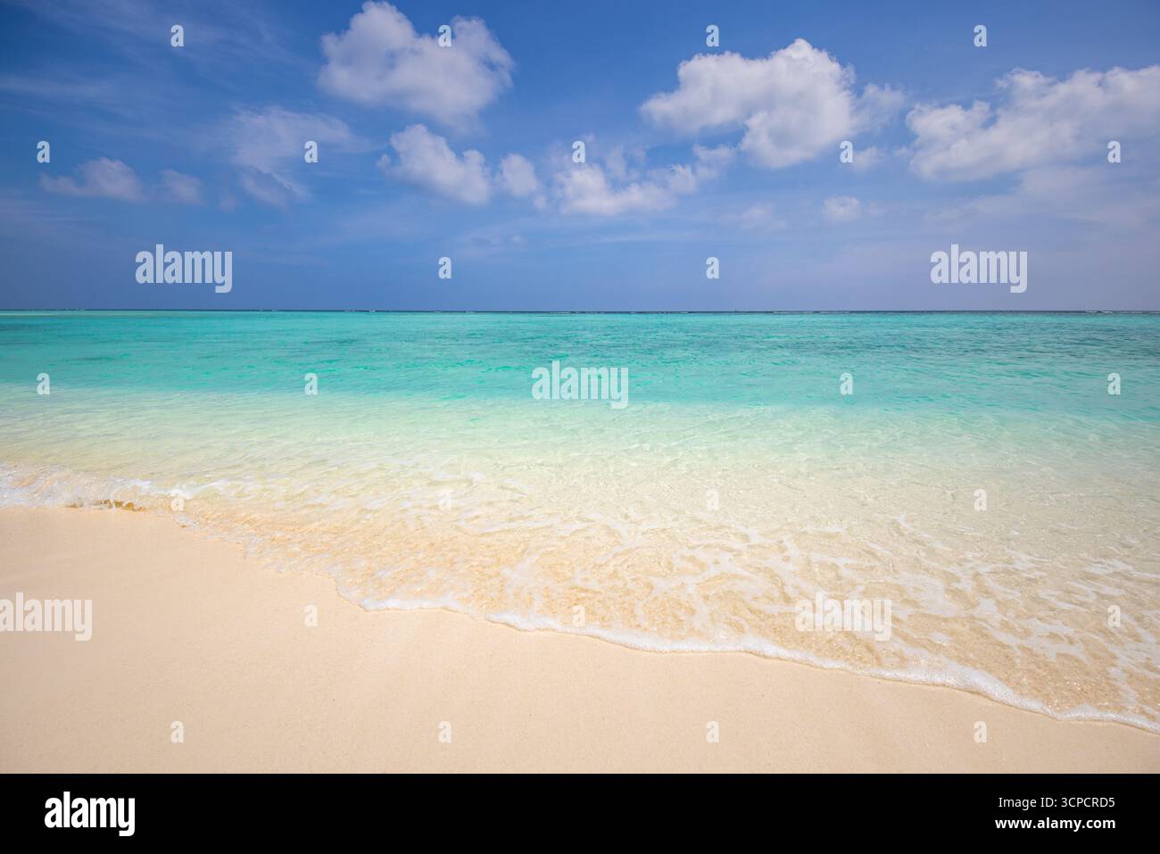 Soleggiata spiaggia estiva con rilassante vista mare e cielo di sabbia che creano una tranquilla scena costiera con acqua calma luce brillante e bellezza naturale Foto Stock