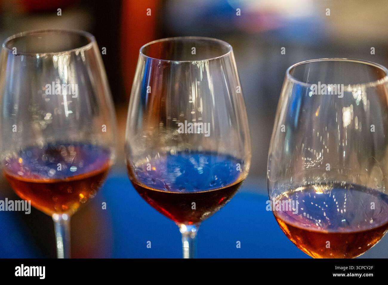 Tre bicchieri di vino o liquori, ciascuno con diversi livelli di liquido, sono allestiti per un evento di degustazione o un incontro sociale, suggerendo un momento di divertimento Foto Stock