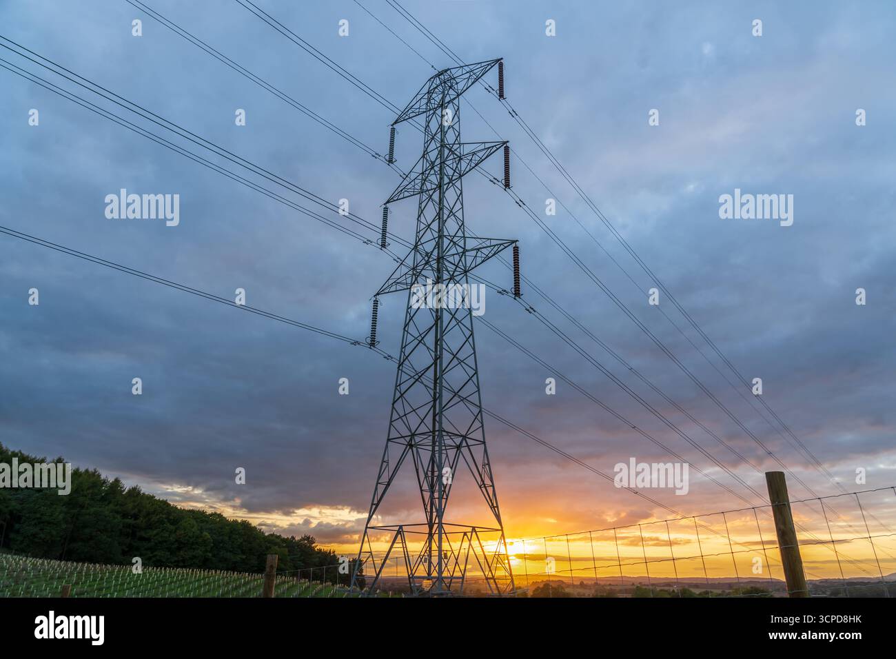 Pilone elettrico del Regno Unito al tramonto, linee elettriche ad alta tensione parte di una moderna infrastruttura elettrica con un cielo colorato Foto Stock