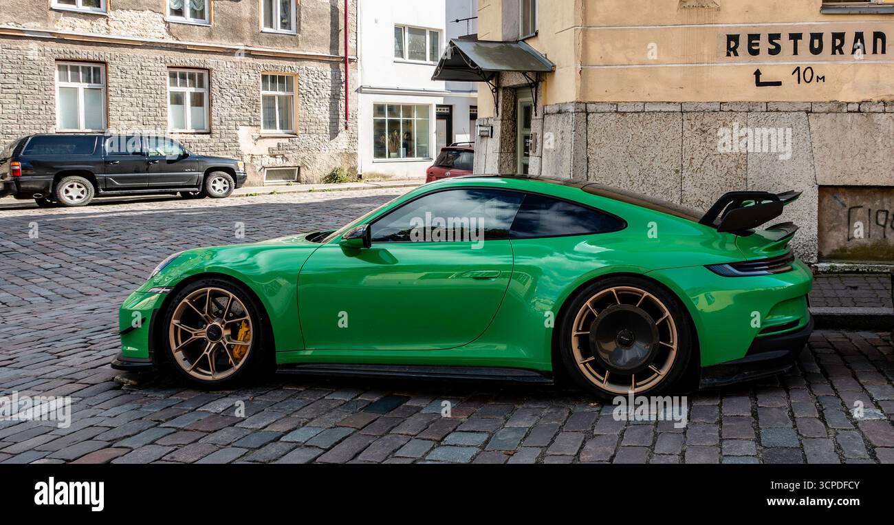 Auto sportiva Porsche 911 GT3 verde parcheggiata in una strada acciottolata a Tallinn, Estonia, con sfondo urbano e design distintivo dell'ala posteriore. Foto Stock