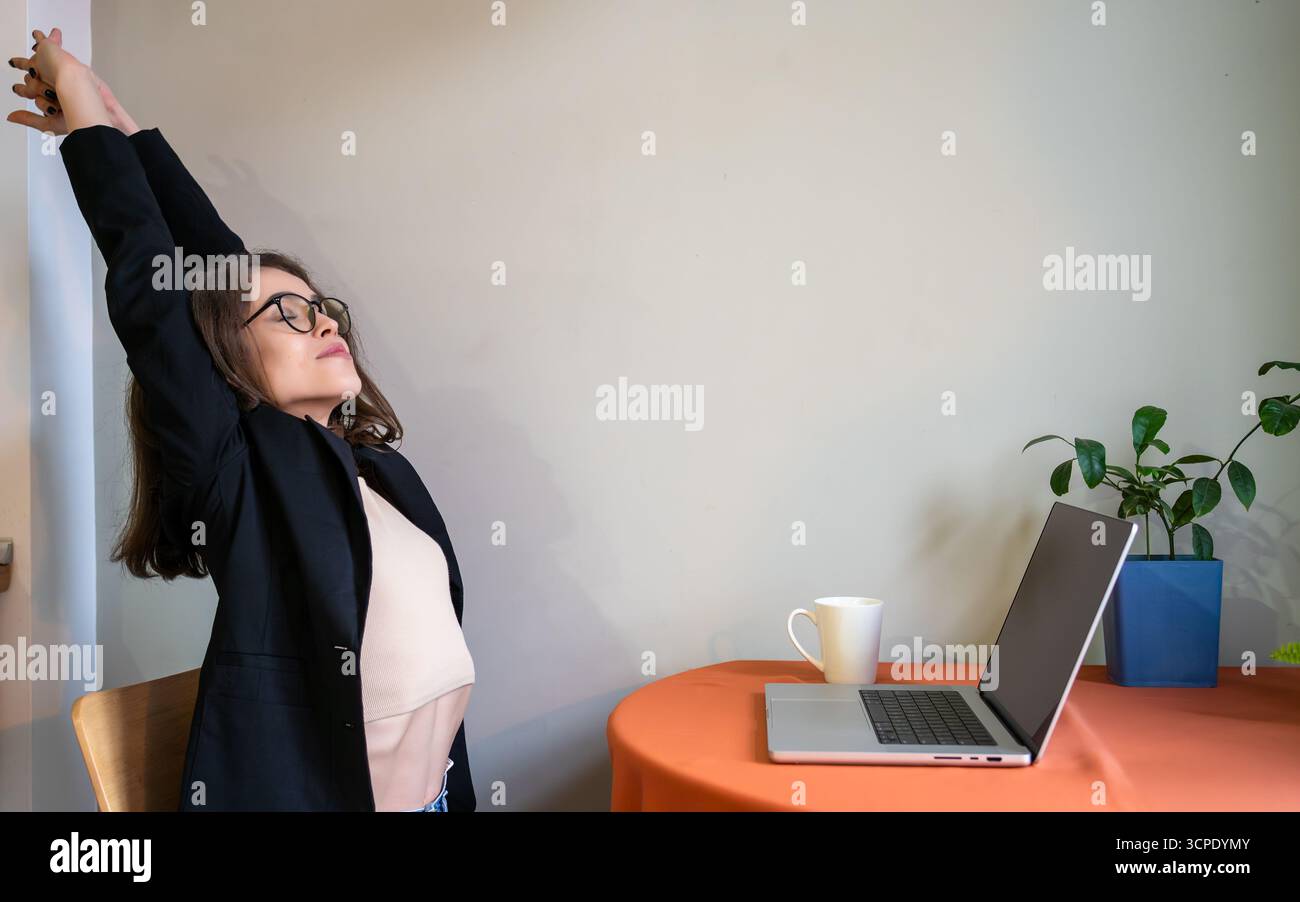 Donna d'affari rilassata braccia stretching ufficio casa lavoro lavoro remoto pausa caffè salute mentale cura di sé produttività concetto di benessere. Foto Stock
