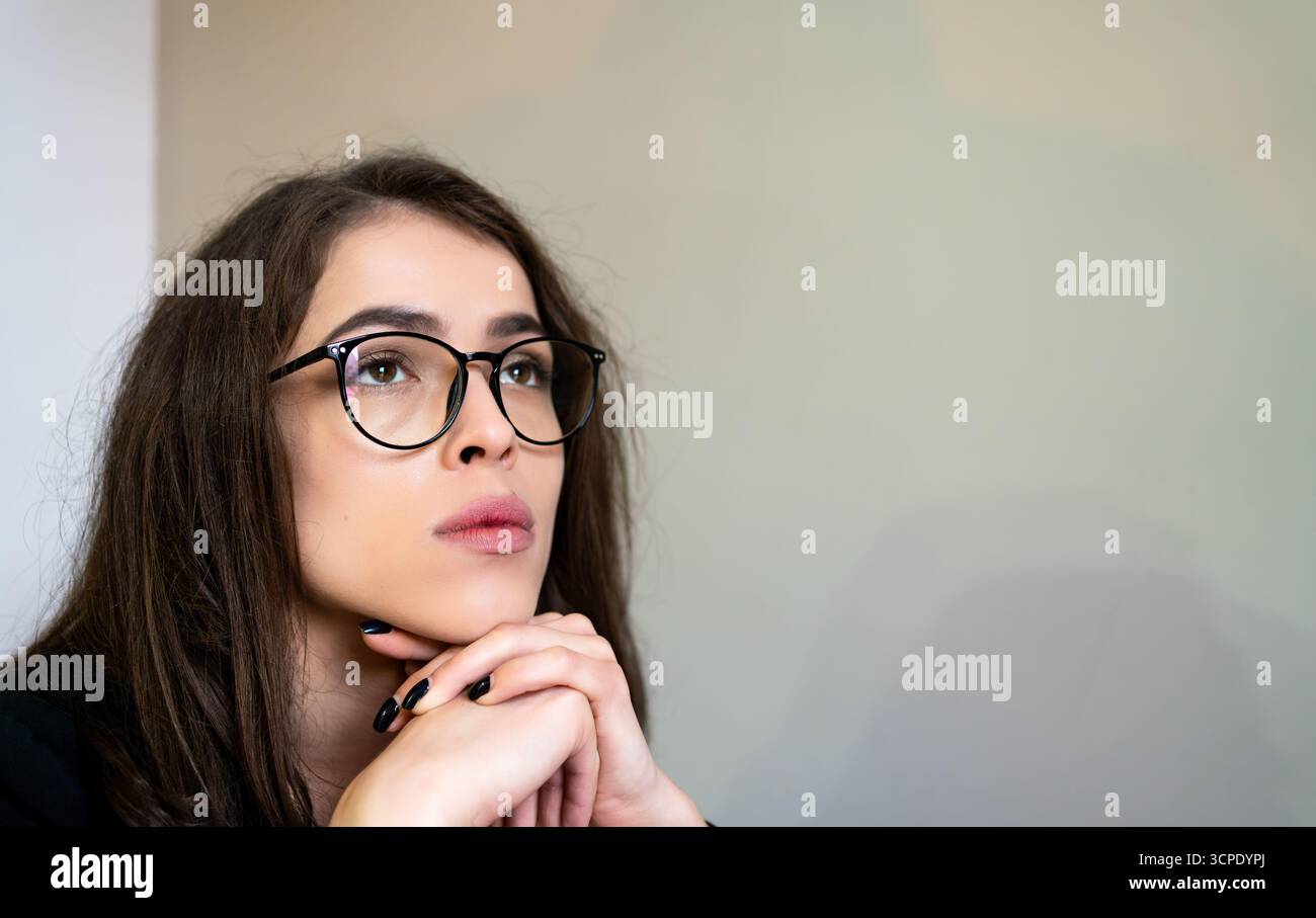 Ritratti giovani e premurosi occhiali da donna che guardano verso l'alto riflettendo idee pianificazione istruzione futura decisioni aziendali carriera concetto di lavoro a distanza. Foto Stock