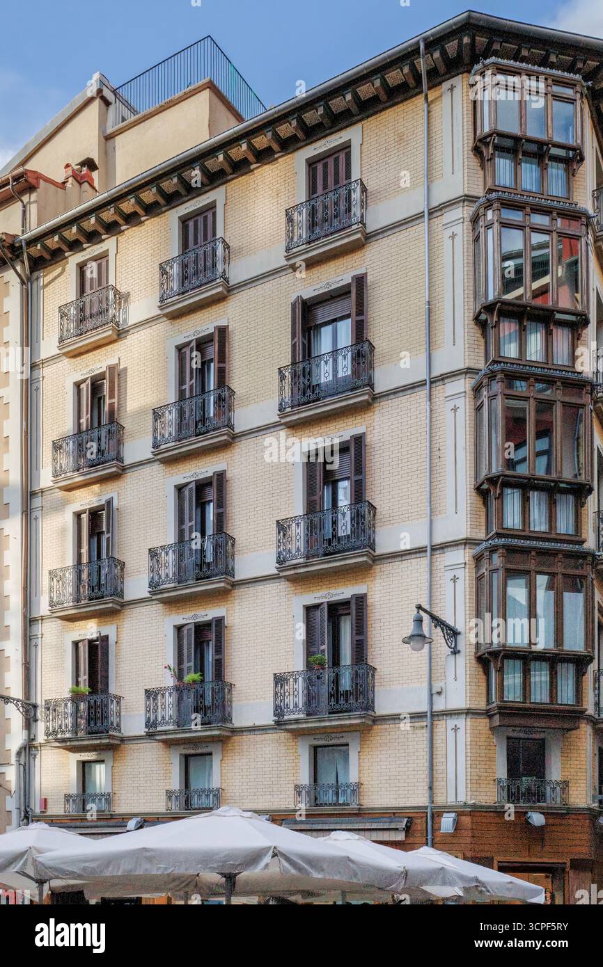 Edificio storico con galleria di vetro a Pamplona Navarra, Spagna. Architettura urbana tradizionale, decorazioni in metallo, balcone chiuso, facciata in mattoni gialli Foto Stock