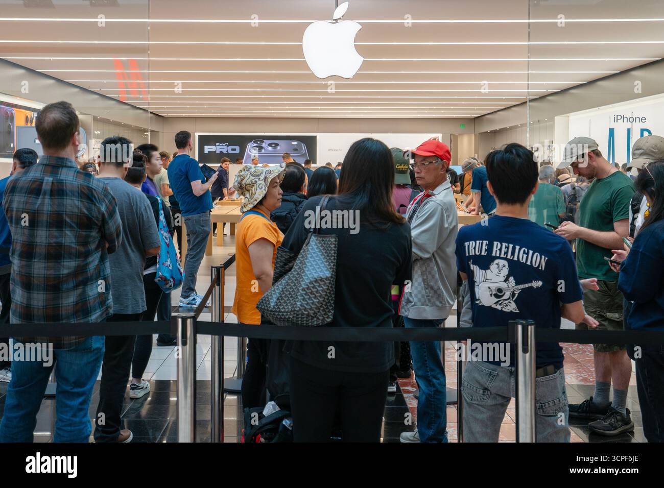Lunghe code di clienti aspettano all'ingresso di un Apple Store nel Washington Square Mall a Tigard, Oregon, venerdì 19 settembre 2025, il ... Foto Stock
