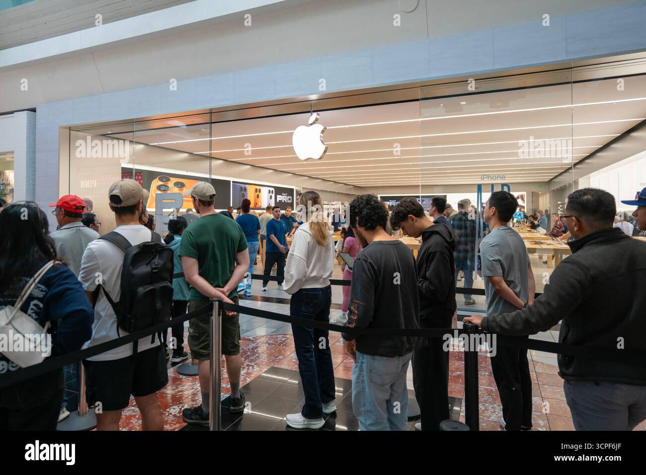 Lunghe code di clienti aspettano all'ingresso di un Apple Store nel Washington Square Mall a Tigard, Oregon, venerdì 19 settembre 2025, il ... Foto Stock