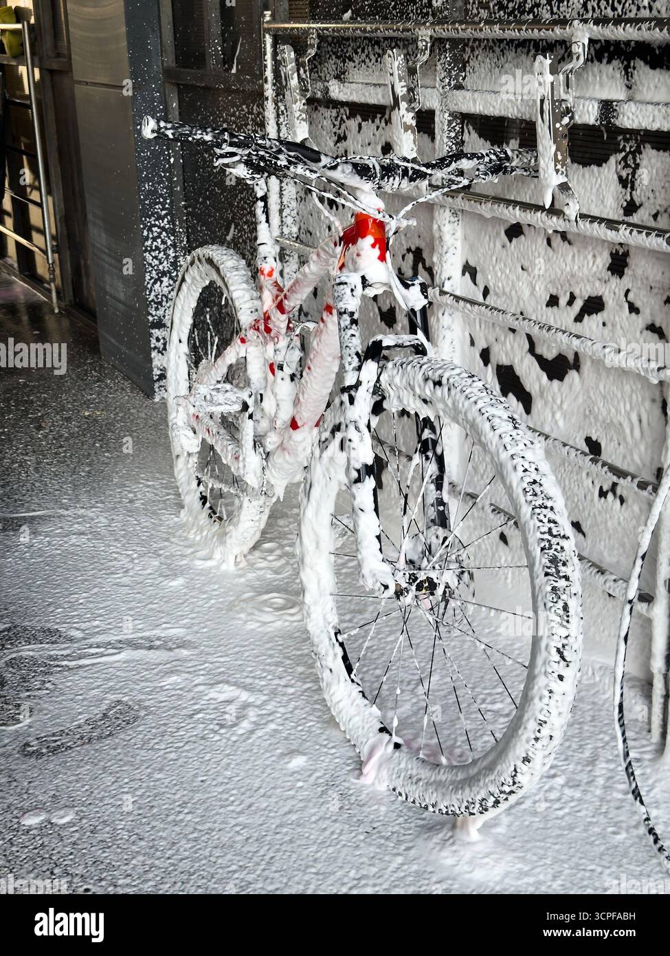 Lavare una bicicletta con schiuma in un autolavaggio self-service. Cura della bicicletta. Foto Stock