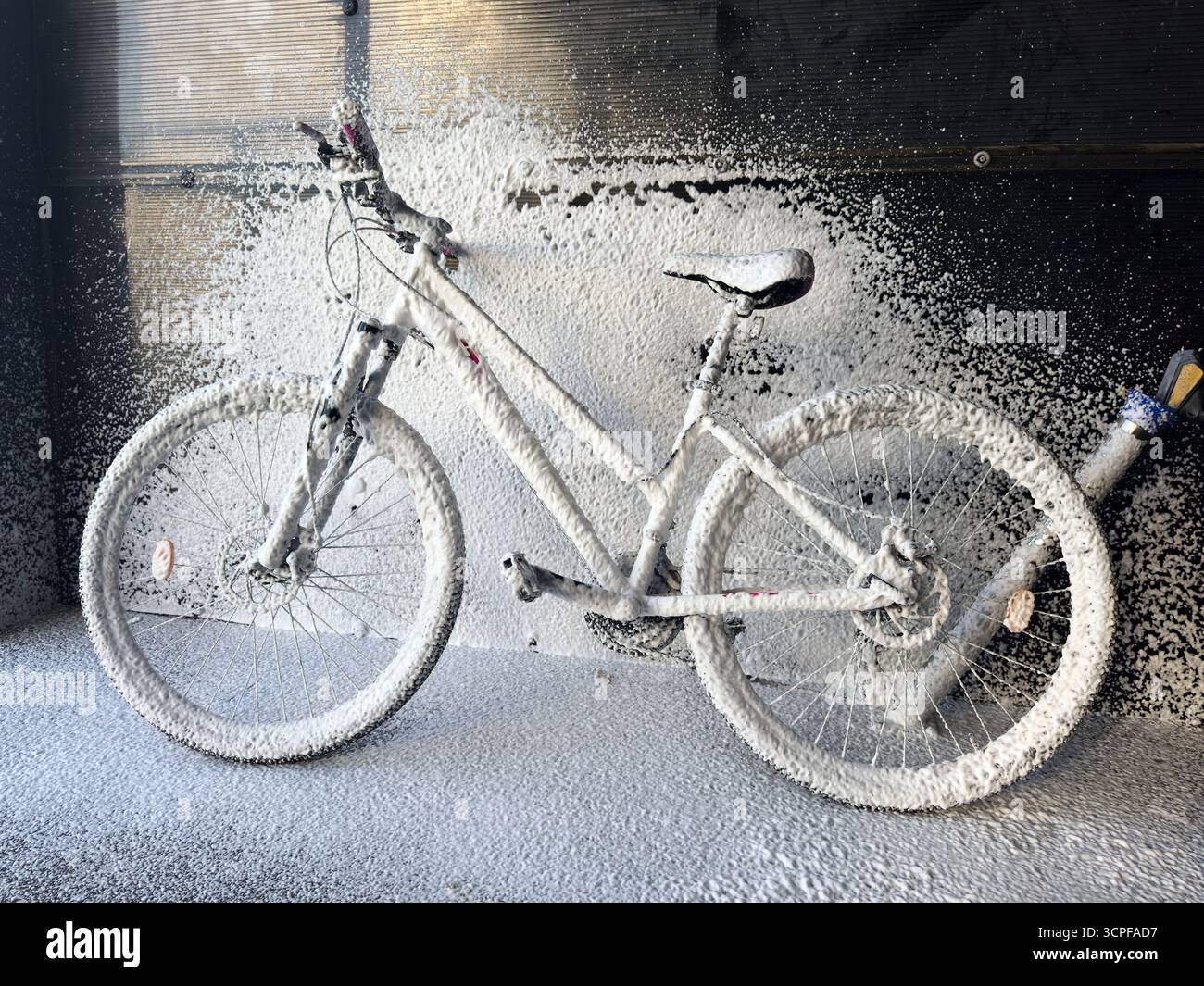 Lavare una bicicletta con schiuma in un autolavaggio self-service. Cura della bicicletta. Foto Stock