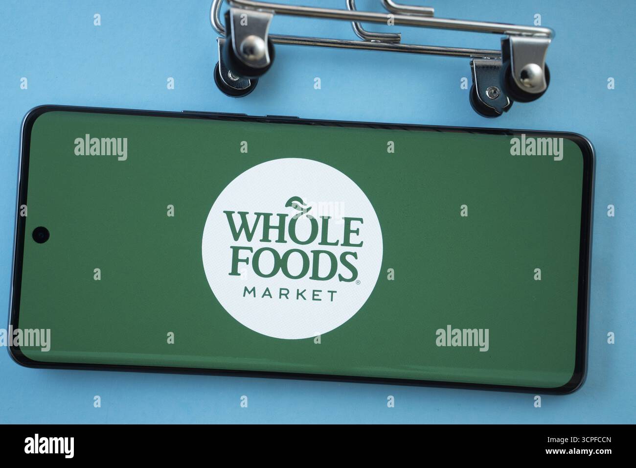 Dhaka, Bangladesh - 3 luglio 2025: Schermo dello smartphone che mostra il logo Whole Foods Market con ruote del carrello su sfondo blu Foto Stock