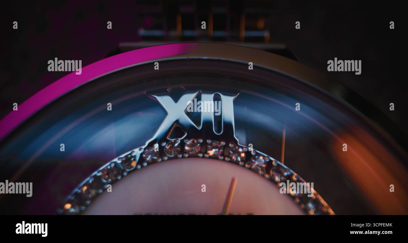 Primo piano di un elegante orologio da polso con lunetta in pietra preziosa e bracciale metallizzato che mostra l'ora esatta. Accessorio che simboleggia il design di lusso, la precisione, la moda e il concetto simbolico del tempo in stile moderno. Foto Stock