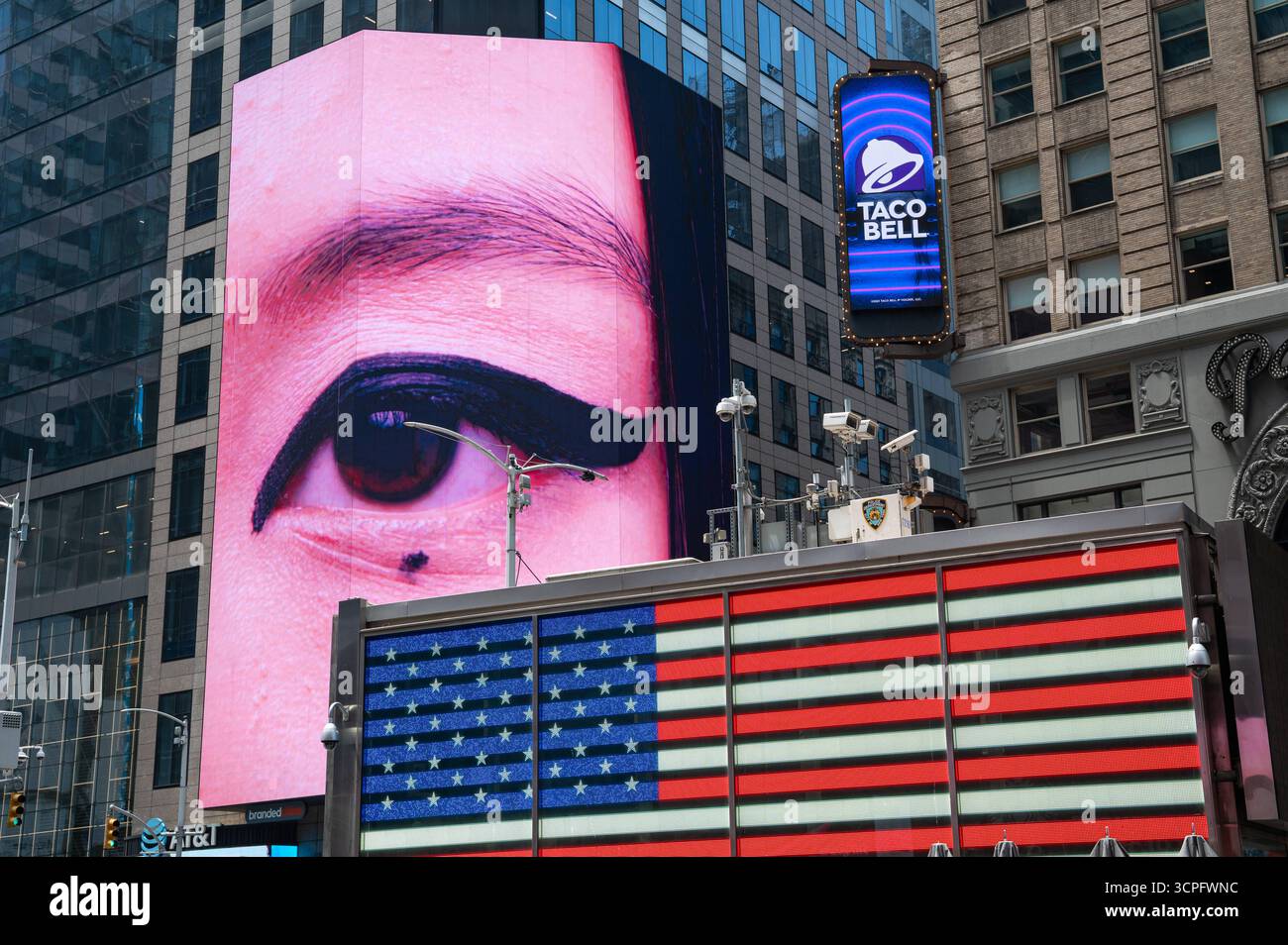 30.05.2025, Manhattan, New York City, New York, Vereinigte Staaten USA - Eine hinterleuchtete US-Flagge auf einer LED-Anzeige an der Rekrutierungsstation der US-Streitkraefte strahlt vor einem digitalen Werbedisplay mit einem riesigen asiatischen Auge am Times Square a Midtown Manhattan. *** 30 05 2025, Manhattan, New York City, New York, Stati Uniti USA Una bandiera statunitense retroilluminata su un display a LED presso la US Armed Forces Recruiting Station brilla di fronte a un display pubblicitario digitale con un gigantesco occhio asiatico a Times Square, Midtown Manhattan Foto Stock
