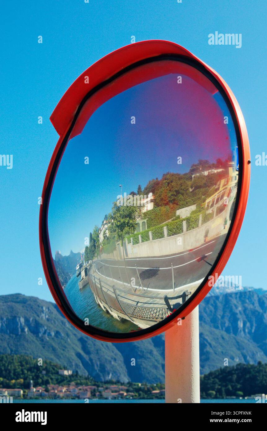 Specchio convesso per la sicurezza stradale che riflette il paesaggio del lago di Como, Italia Foto Stock