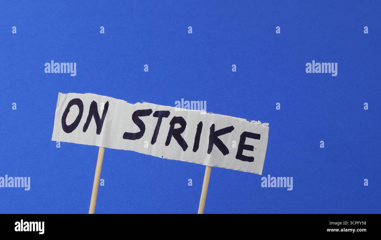 Sciopero scritto su un cartello di protesta con sfondo blu Foto Stock