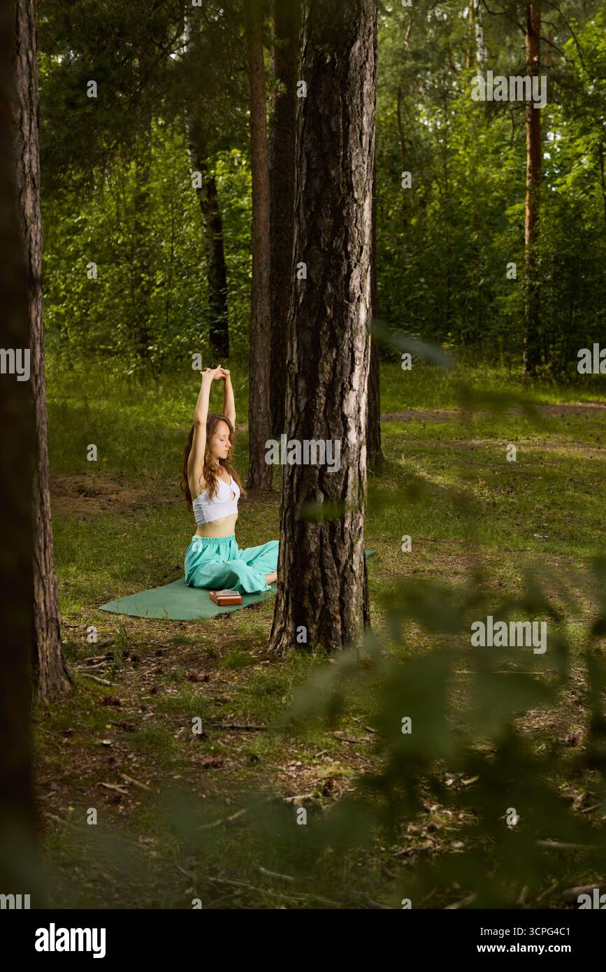 Donna che pratica yoga in un ambiente tranquillo nella foresta in estate Foto Stock