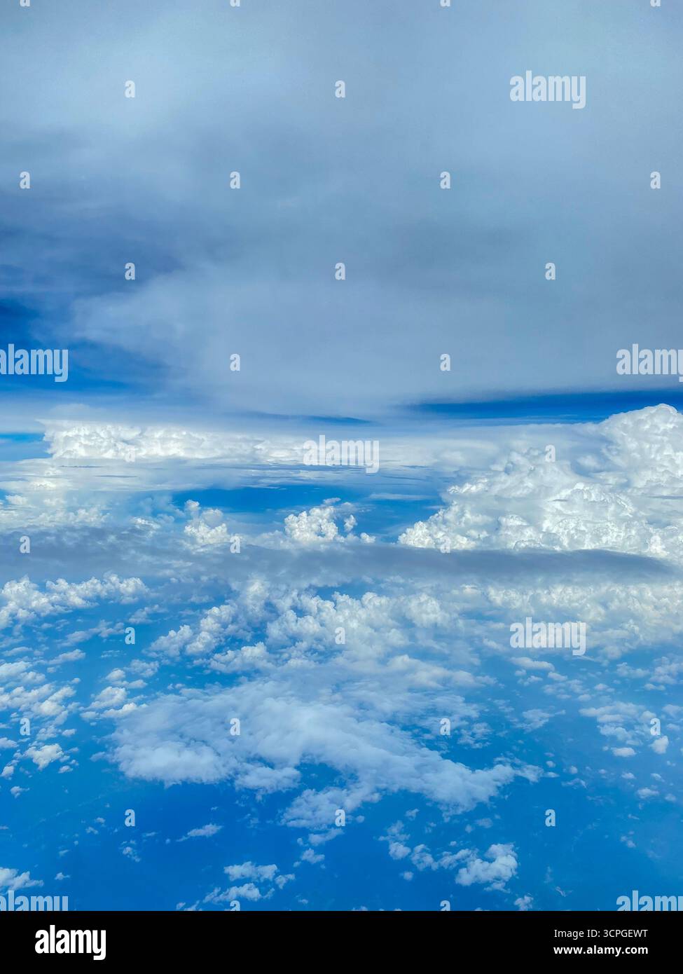 Vista di un passeggero aereo attraverso l'oblò o la finestra dell'aereo sopra il cielo blu tropicale con strati di nuvole sullo stretto di Malacca che si separano Foto Stock