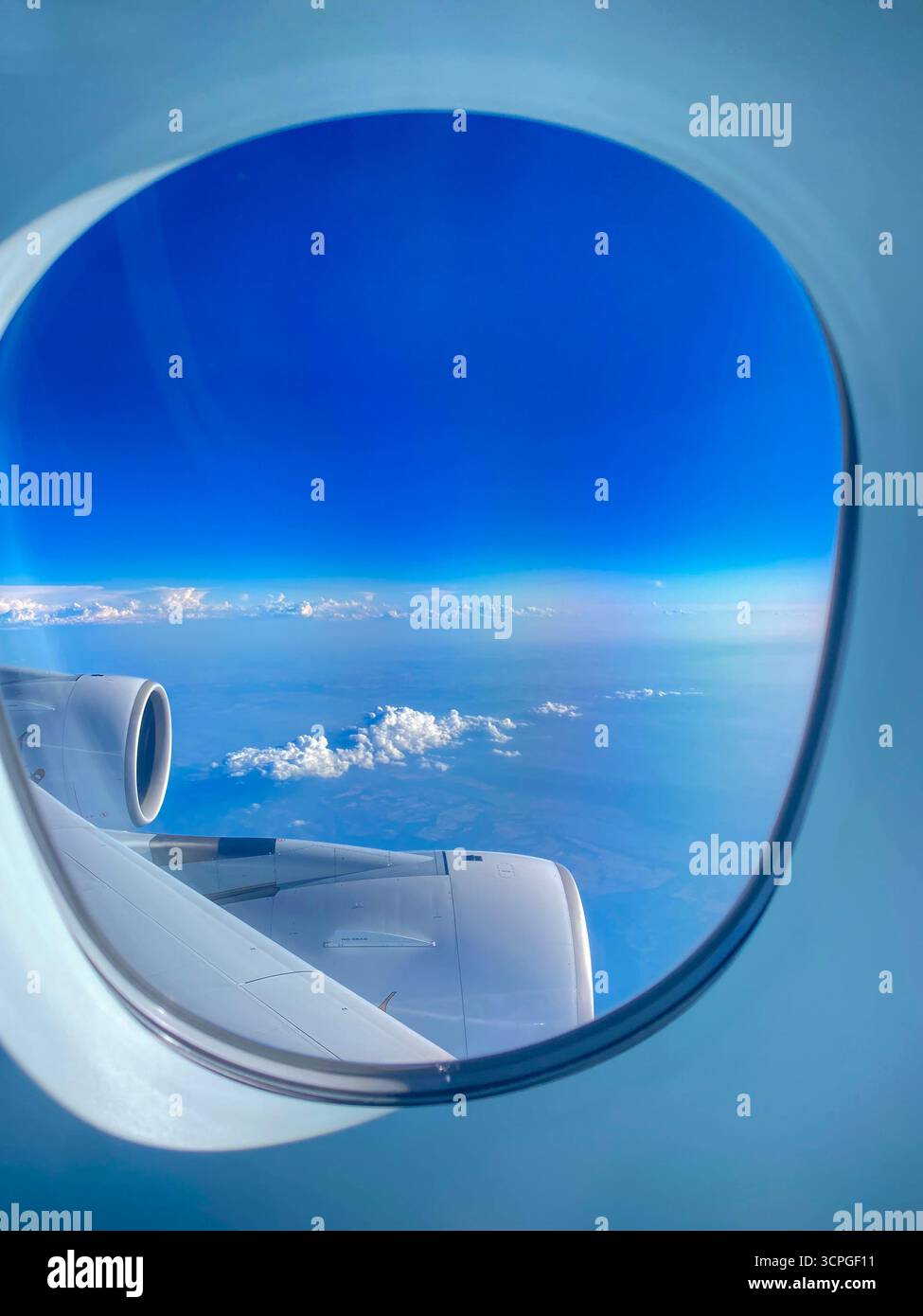 Vista di un passeggero aereo attraverso l'oblò o la finestra dell'aereo sopra il cielo blu con nuvole sparse sulla Turchia in Europa. Foto Stock