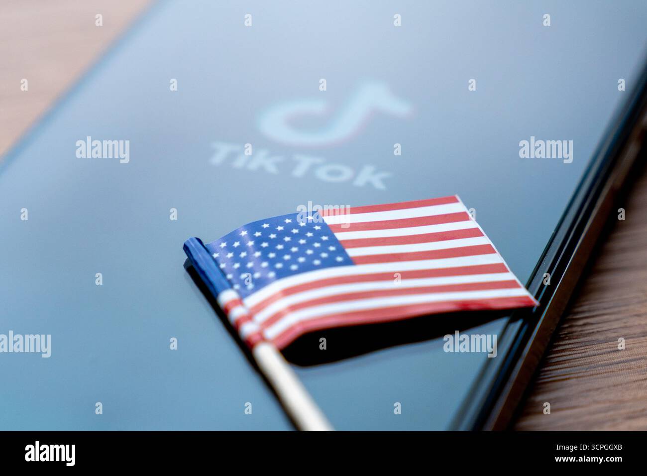 Una piccola bandiera americana e uno smartphone con il logo e il nome TikTok. Social media, concetti di sicurezza dei dati. Foto Stock