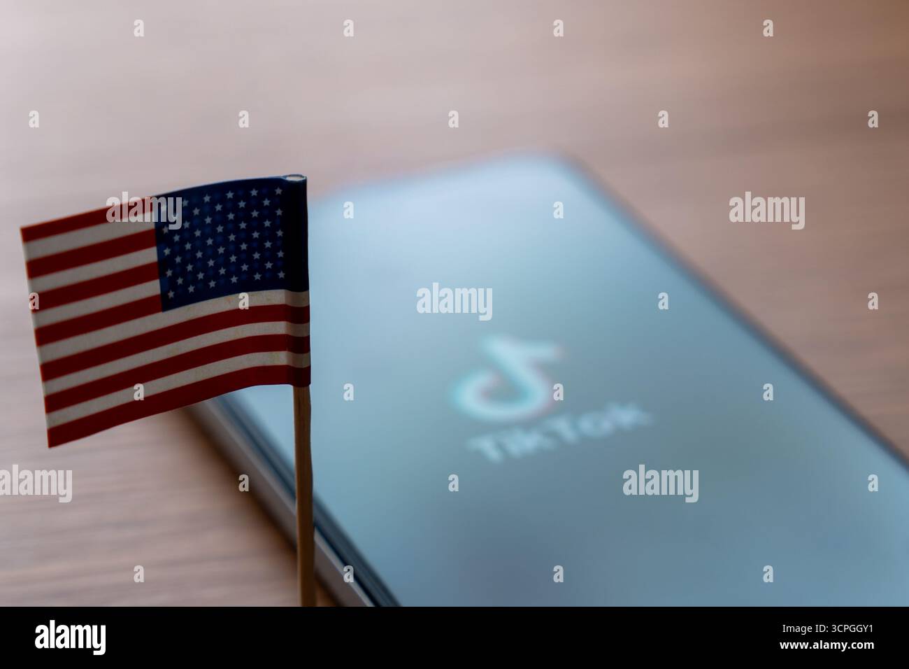 Una piccola bandiera americana e uno smartphone con il logo e il nome TikTok. Social media, concetti di sicurezza dei dati. Foto Stock