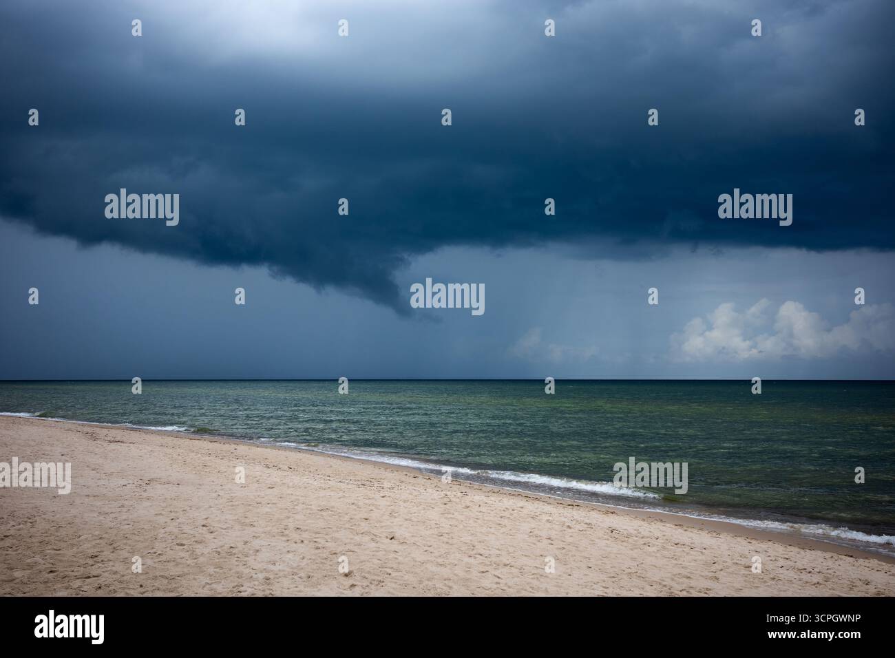 Nuvole di tempesta pesanti e scure si riuniscono sull'orizzonte del mare. Acque verdi e calme prima che il tempo cambi. Foto Stock