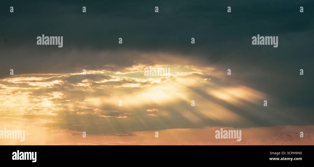 Cielo tranquillo e colorato al tramonto con luce del sole nascosta dietro nuvole luminose, creando sfumature morbide e magica armonia visiva. Foto Stock