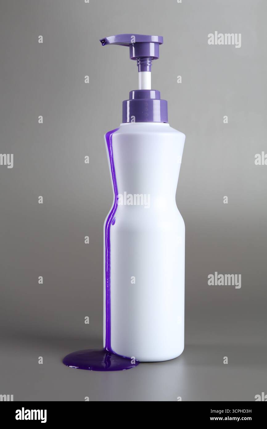 Prodotto per la cura dei capelli biondi in bottiglia su sfondo grigio Foto Stock