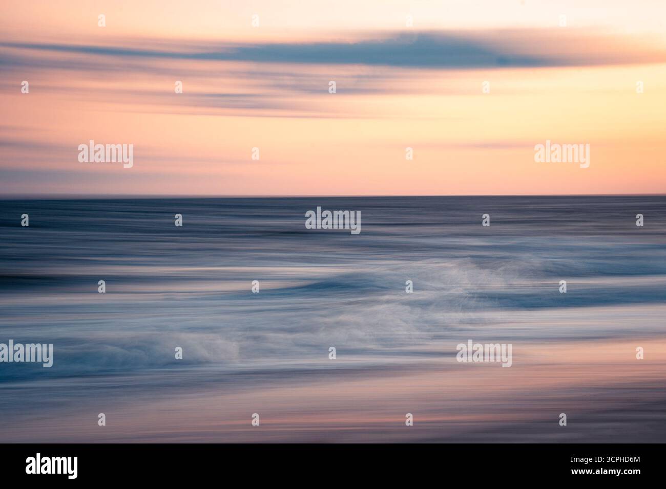 Lunga esposizione astratta del mare sulla spiaggia al tramonto con movimento fluente dell'acqua marina dell'oceano e cielo colorato Foto Stock