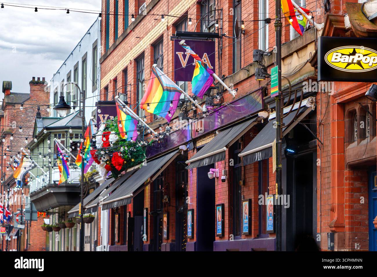 scena gay di canal street con bandiere arcobaleno colorate appese agli edifici del villaggio gay di manchester nel regno unito che celebrano la diversità Foto Stock