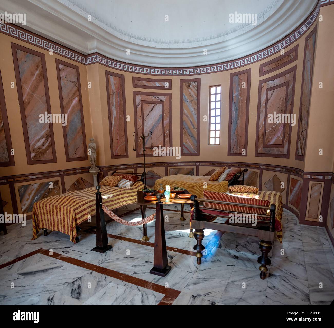 Puras, Spagna - 25 marzo 2025: Antica camera in stile romano con pavimenti in marmo, pareti ornate e mobili d'epoca. Foto Stock