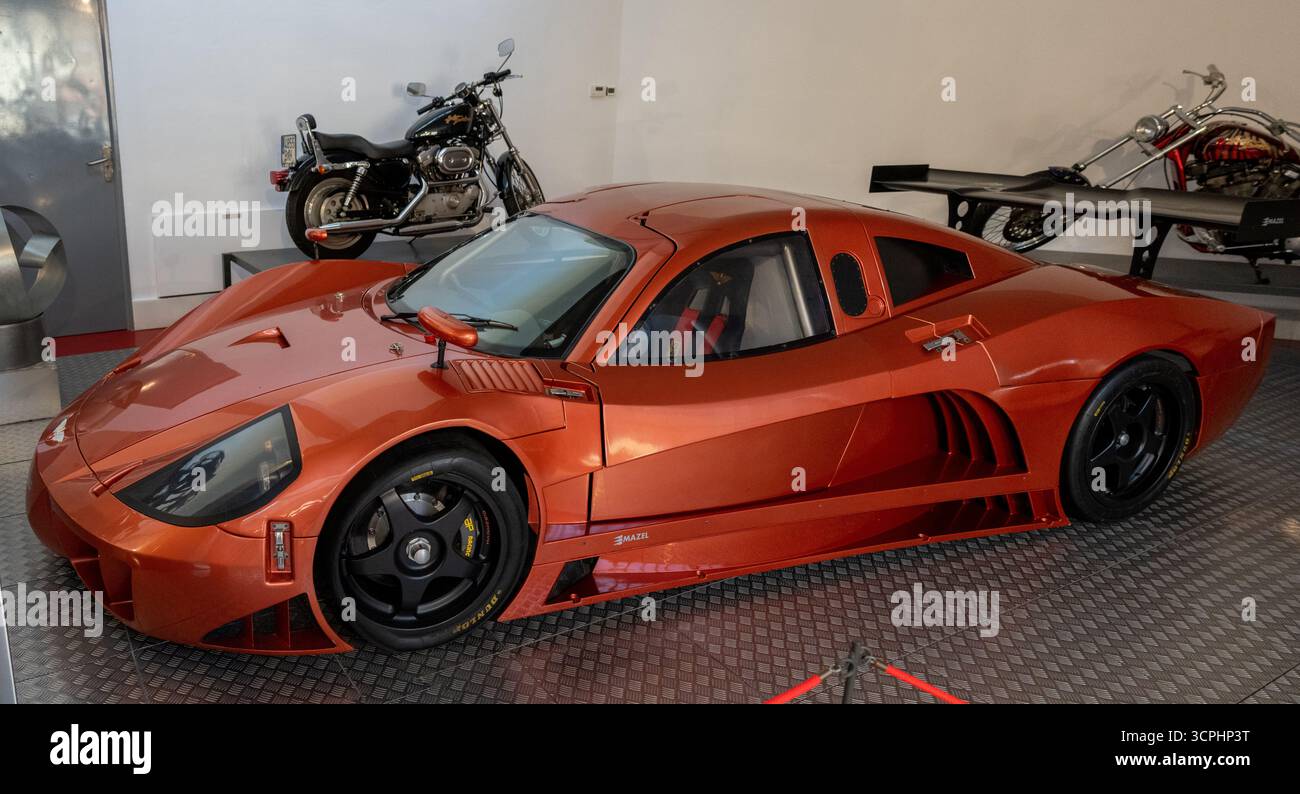 Salamanca, Spagna - 25 marzo 23: Un'elegante auto sportiva arancione dal design futuristico, presentata in un moderno ambiente da garage, con una moto in t Foto Stock