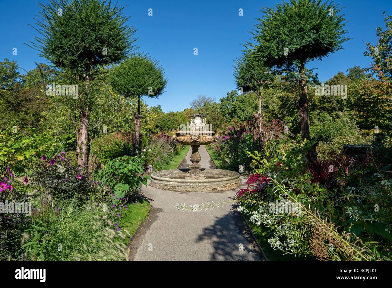 Vista verso la fontana italiana di marmo rosso di Verona tra i doppi confini del Wall Garden a Nymans, West Sussex, Inghilterra, Regno Unito. Foto Stock