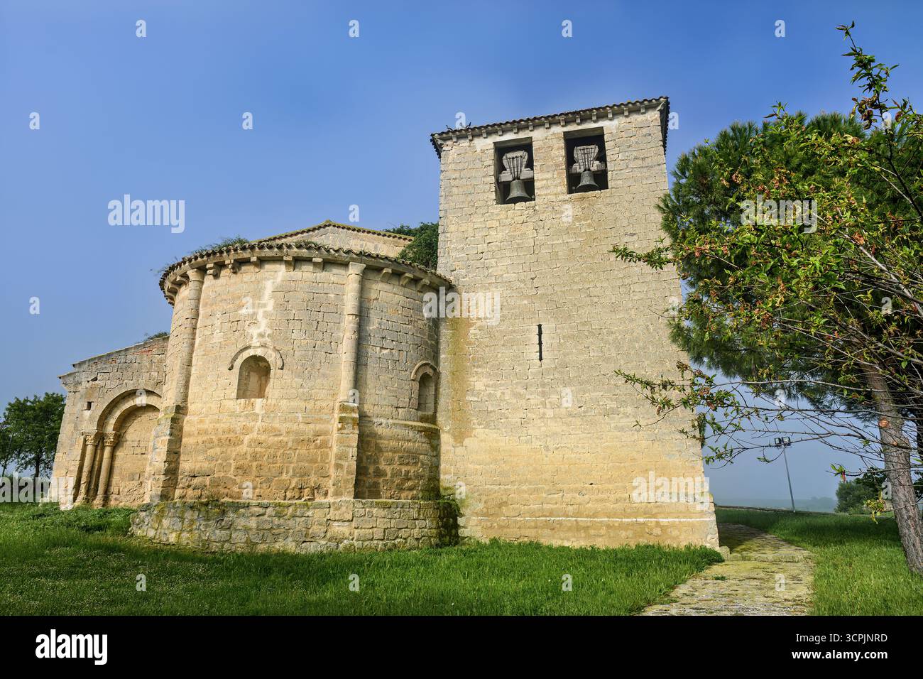 Storica chiesa romanica con abside e campanile in un tranquillo paesaggio rurale Foto Stock
