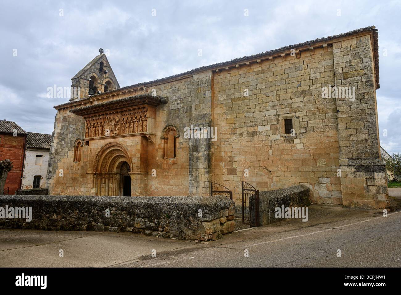 Storica chiesa romanica con portale decorato scolpito, campanile in pietra e robuste pareti in muratura. Foto Stock