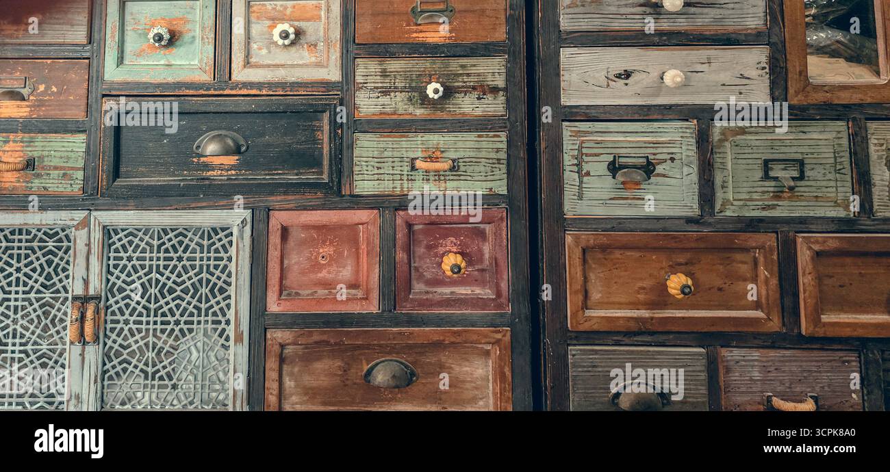 Primo piano con cassetti in legno vintage. Vecchio cassettiera colorata fatta a mano e sfondo degli armadi. Foto Stock