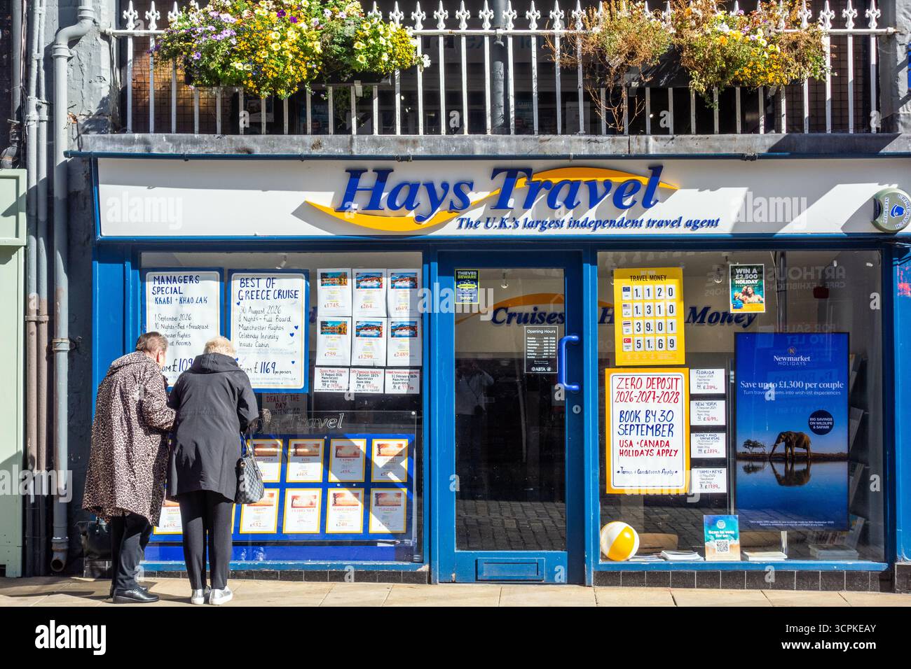 Due anziani pensionati di vecchiaia che guardano alla finestra delle agenzie di viaggio di Hays nella città di Chester nel Cheshire Foto Stock
