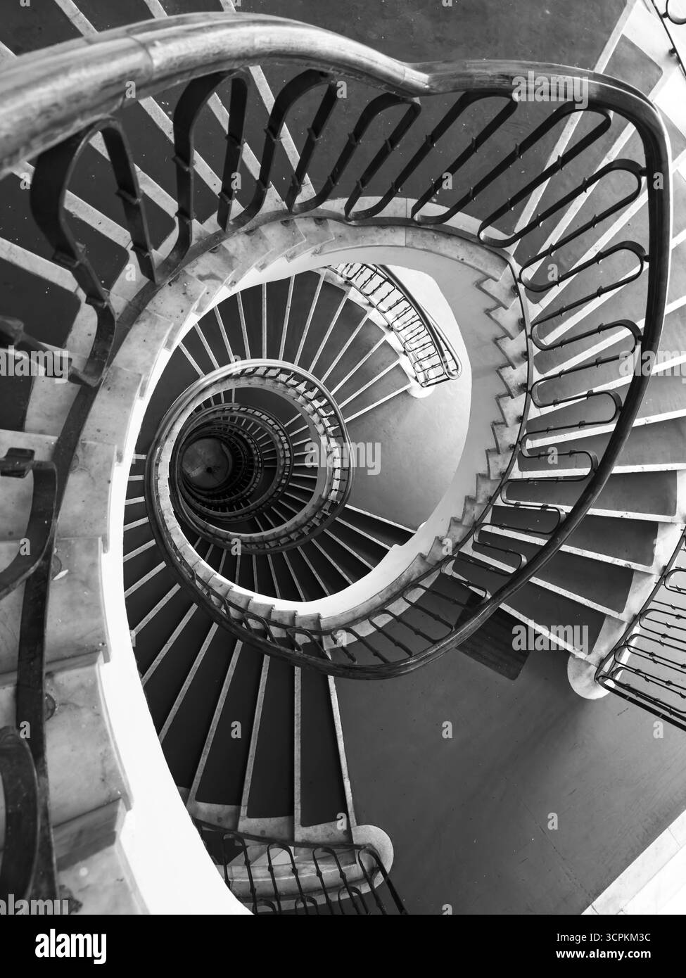 Scala a chiocciola in bianco e nero vista dall'alto che sottolinea la profondità delle curve e il design architettonico Foto Stock