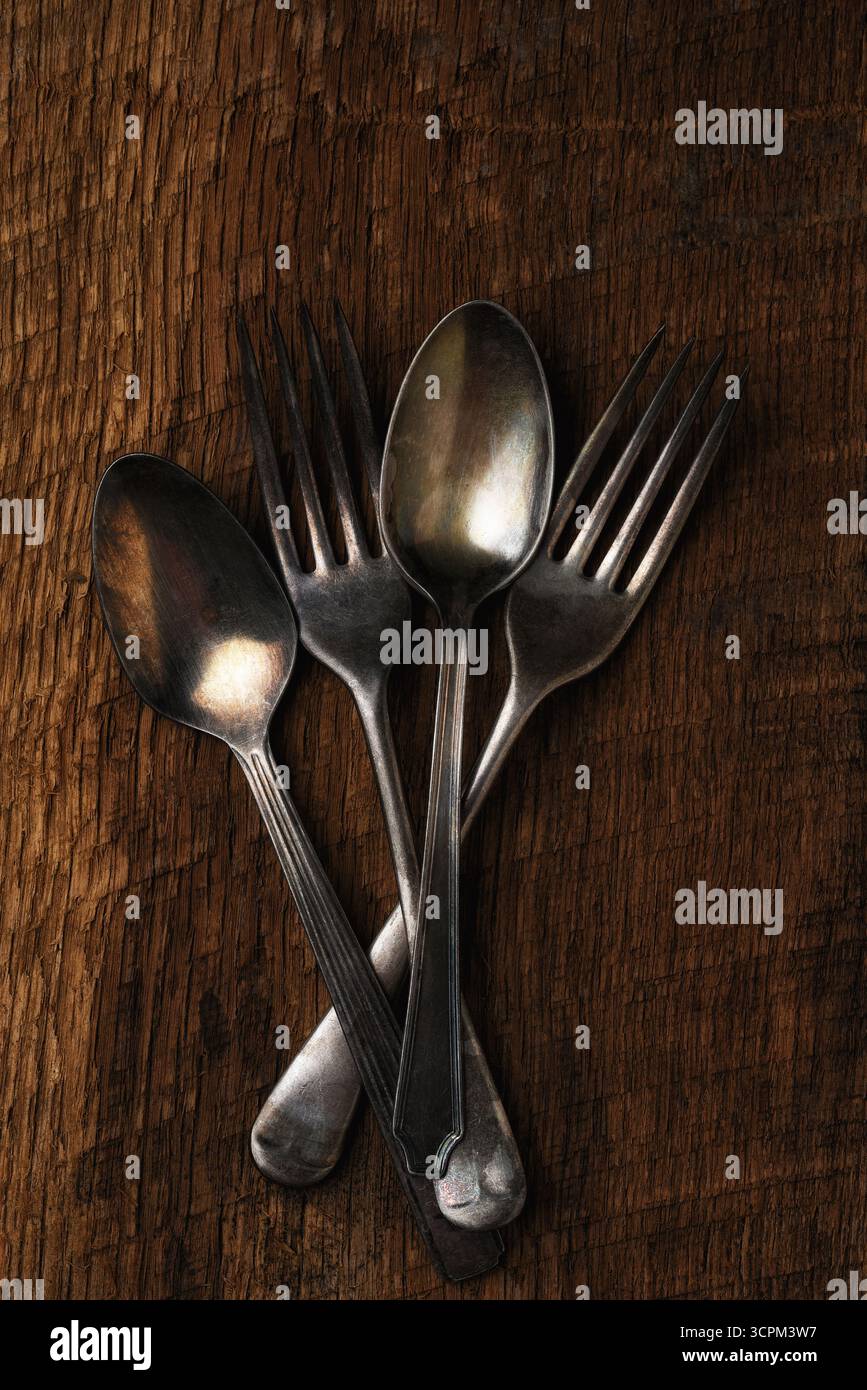 Oggetti di antiquariato ancora in vita. Angolo di inclinazione shoto di due cucchiai e due forchette su un tavolo in legno rustico. Foto Stock