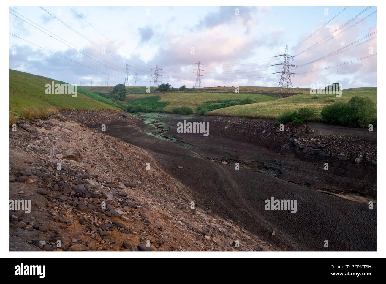 Il letto del Baitings Reservoir, con solo un piccolo ruscello rimasto, mette in evidenza il grave impatto delle condizioni di siccità. Foto Stock