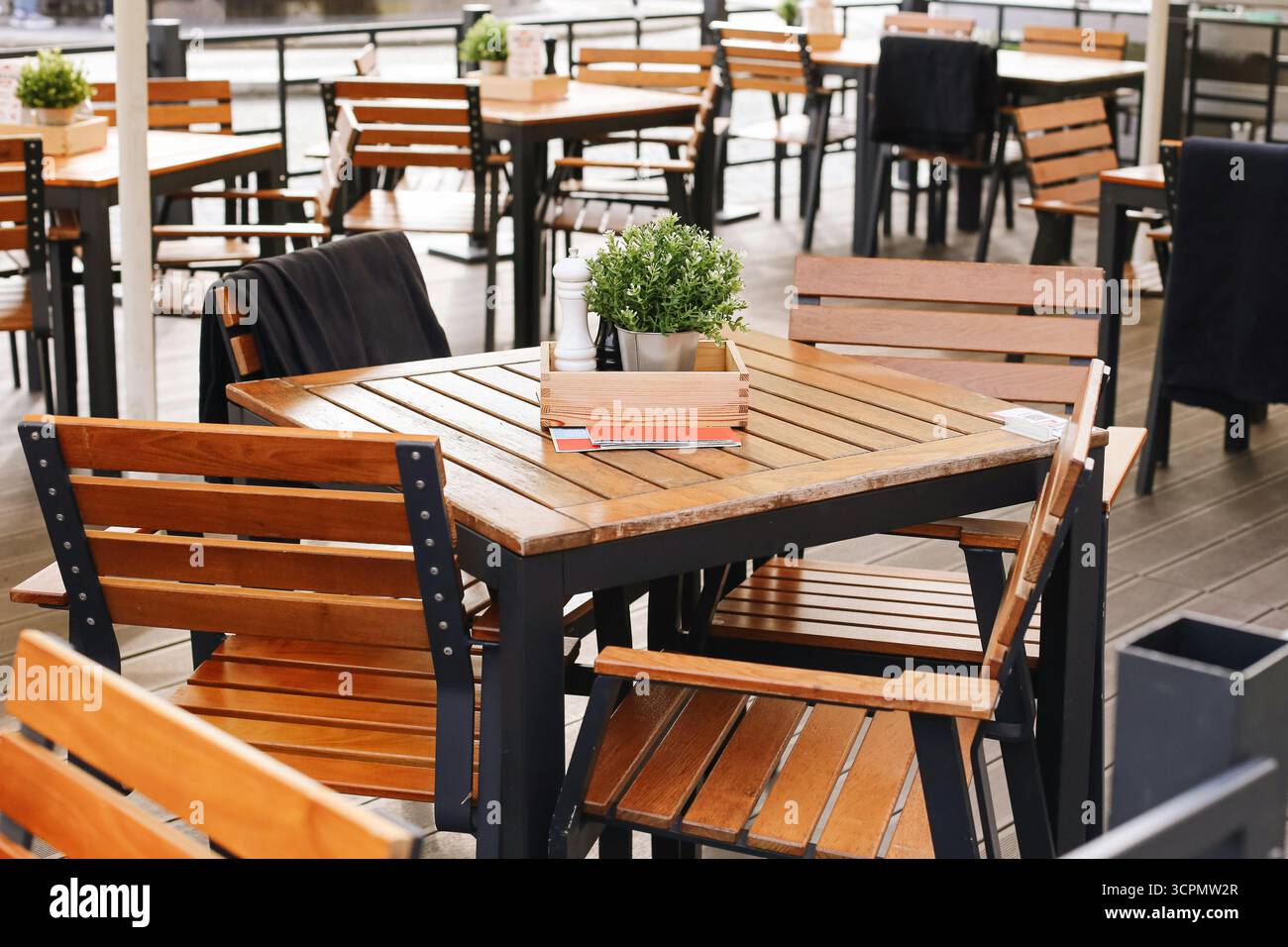 Terrazza caffetteria all'aperto con tavoli e sedie in legno. Mobili vuoti del ristorante disposti all'esterno. Area pranzo all'aperto per gli ospiti. Foto Stock