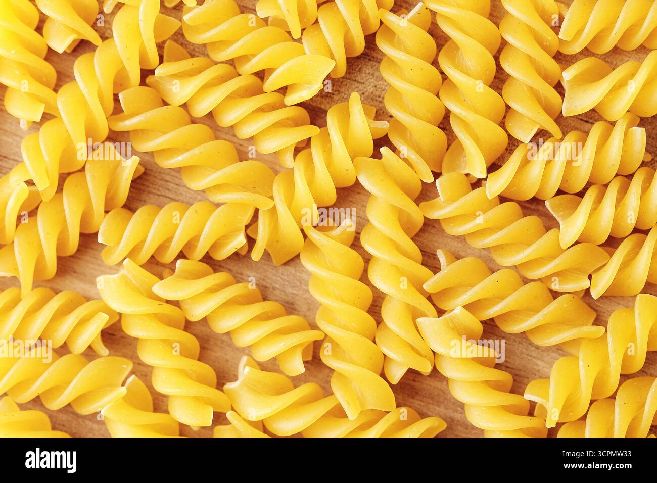 Primo piano di pasta fusilli cruda. Fondo a spirale giallo con macaroni. Ingrediente alimentare italiano per cucinare. Prodotto di frumento secco. Carboidrati sani. Foto Stock