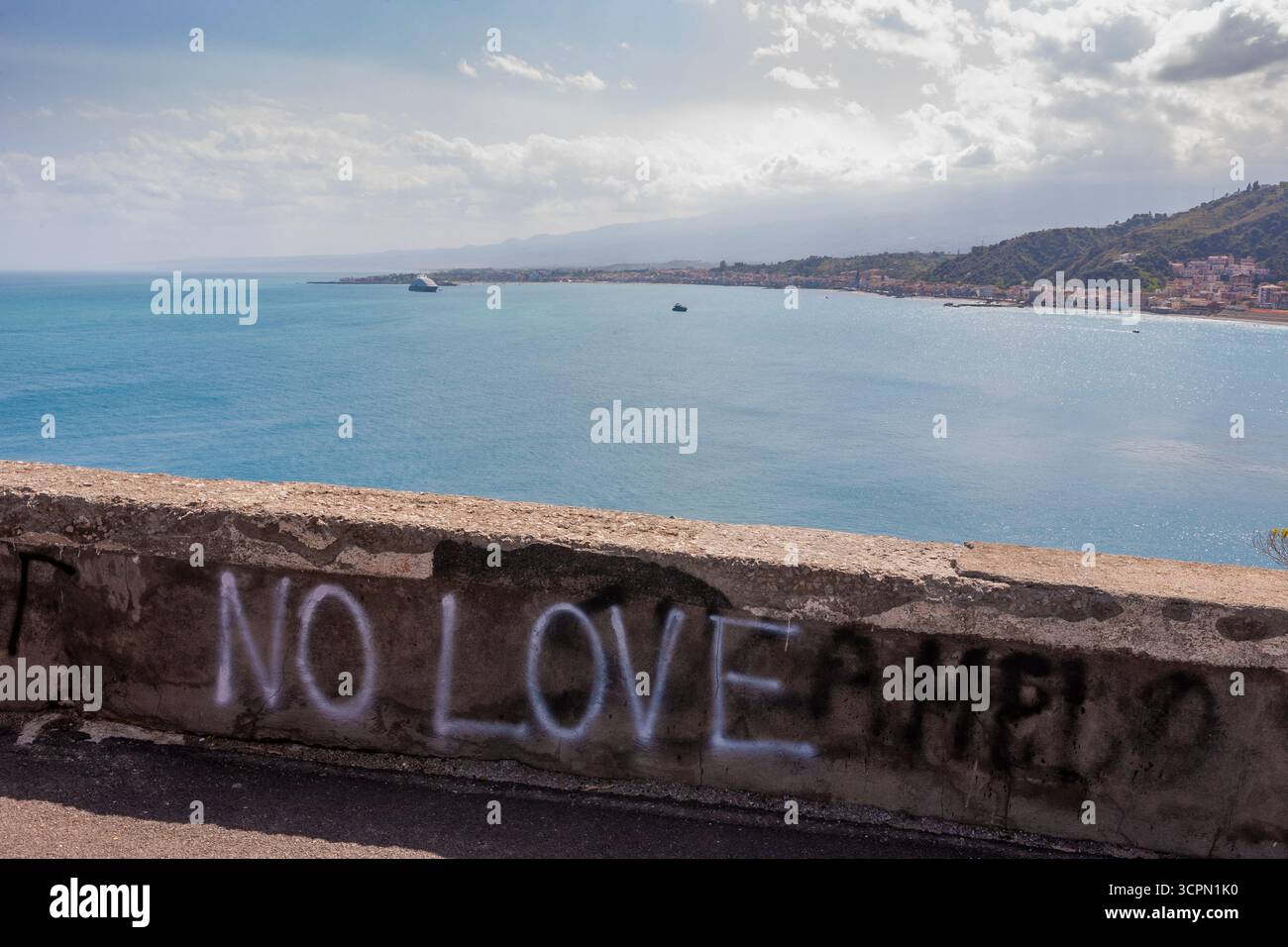 Triste e deprimente graffito su un muro di Taormina, con vista sul Golfo di Giardini Naxos: Sicilia, Italia Foto Stock