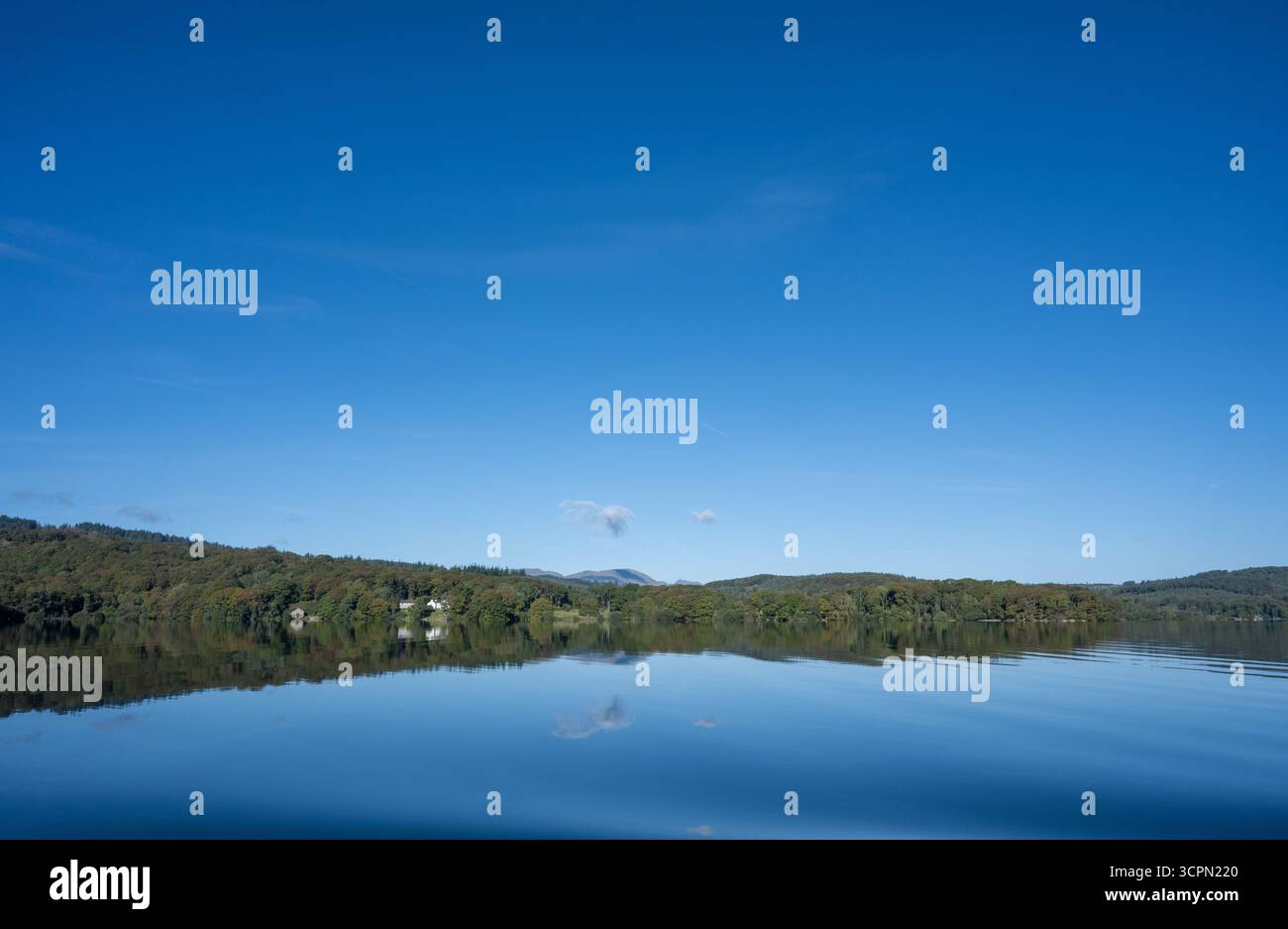 Vista panoramica di Windermere con riflessi di alberi e colline lontane, Lake District National Park, Cumbria, Inghilterra Foto Stock