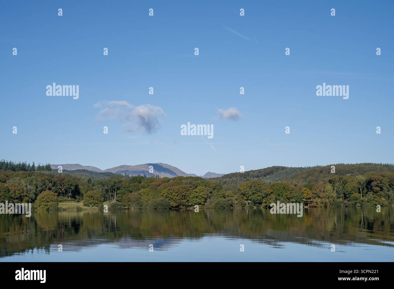 Vista panoramica di Windermere con riflessi di alberi e colline lontane, Lake District National Park, Cumbria, Inghilterra Foto Stock